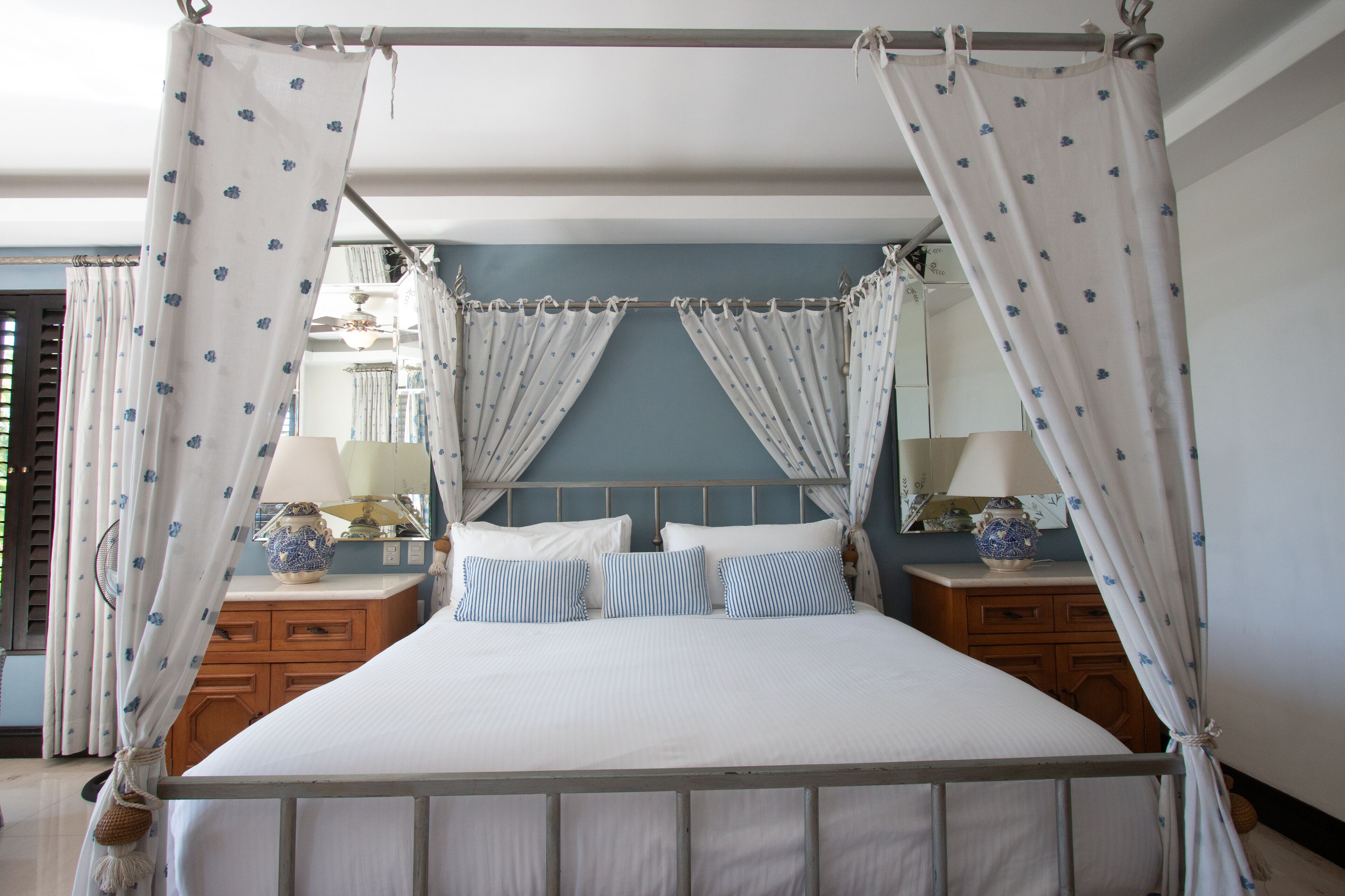 A four-poster canopy bed with white bedding and blue floral curtains.