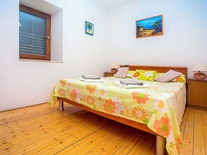 A bedroom with a wooden floor, a bed with a floral bedspread, two bedside lamps, a window with blinds, and a framed picture on the wall. - Stunning private villa for 8 guests with WIFI, A/C, private pool, hot tub, TV and terrace (Solin)