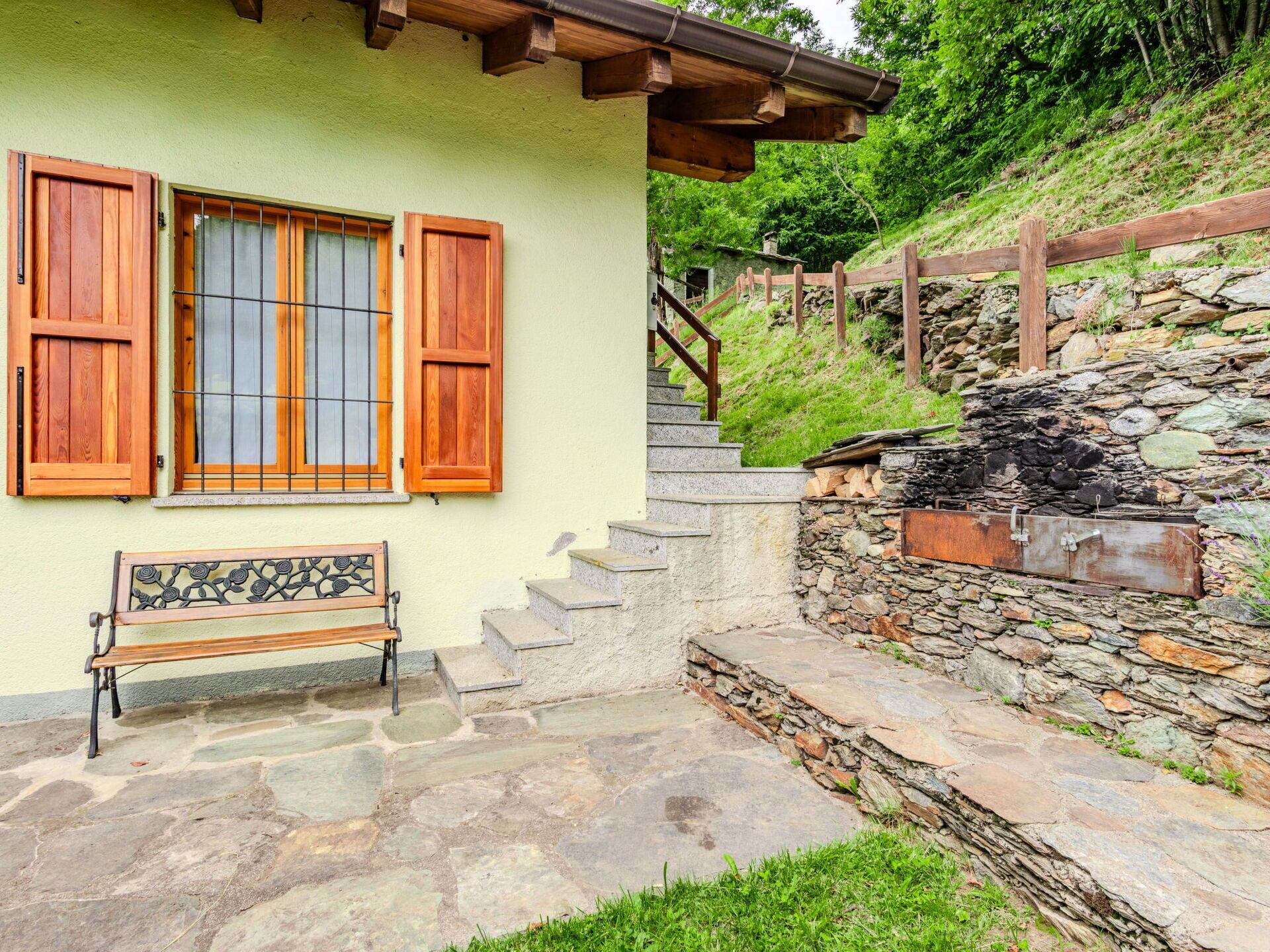 A stone staircase leading to a wooden door, a bench, and a stone wall.