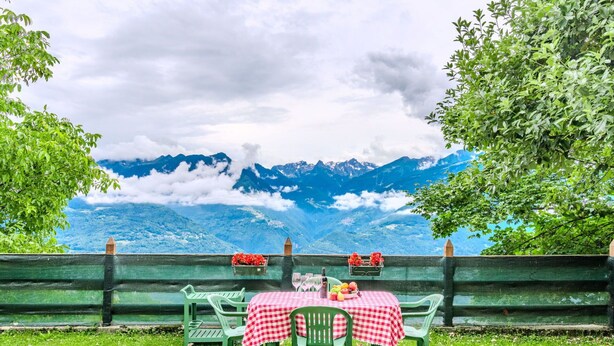 Een eethoek buiten met een tafel voor twee, met uitzicht op een bergachtig landschap.