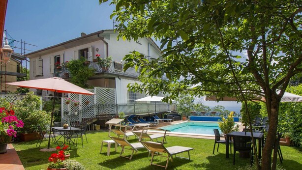 Un espace aménagé au bord de la piscine, avec des chaises longues, une table et un parasol rouge.