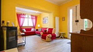 Un salon avec un canapé rouge, un meuble en bois et une fenêtre avec des rideaux.