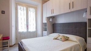 Une chambre à coucher avec un grand lit, une armoire et une porte avec des rideaux.