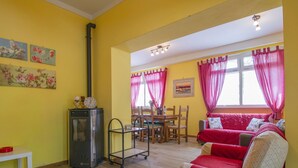 Un salon chaleureux avec un canapé rouge, une table à manger et un coin cuisine équipé d’une cuisinière.