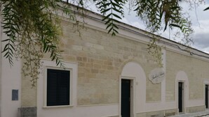 A building with a stone facade, arched doorways, and a sign that reads "Spasich di Saloni." - Cosy apartment for 2 guests with A/C, WIFI, TV and pets allowed (Vernole)
