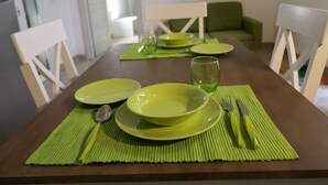 A dining table set with green placemats, plates, a glass, and cutlery. - Cosy apartment for 2 guests with A/C, WIFI, TV and pets allowed (Vernole)