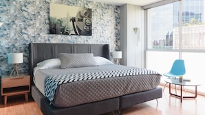 A modern bedroom with a large bed, a cityscape artwork on the wall, and a view of buildings through the window. - Two Hip & Chic Apartments with Private Rooftop in Exclusive Roma Norte (Ciudad de México)