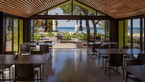 Un espace de restauration intérieur avec des tables et des chaises, de grandes fenêtres et une vue sur la plage.