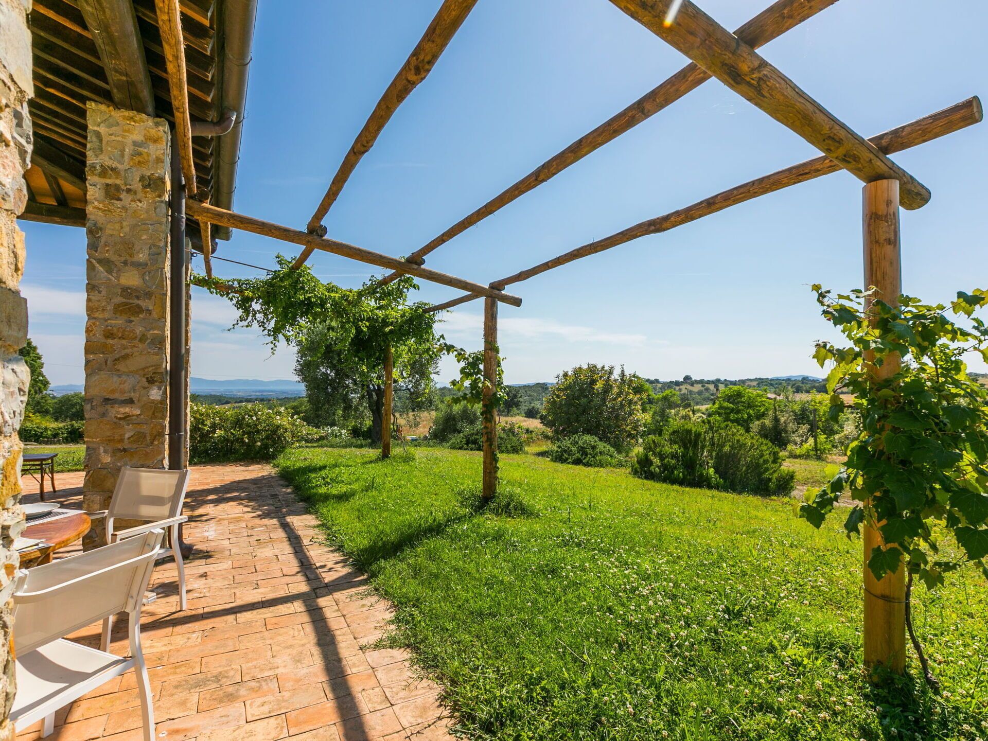 Un área de estar al aire libre cubierta, con paredes de piedra y vistas a un paisaje verde y exuberante.