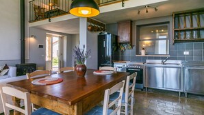 A spacious kitchen with modern appliances, a dining area with a wooden table and chairs, and a staircase leading to an upper level.
