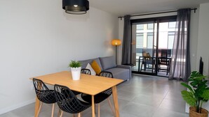 En moderne stue med spisebord, stole, sofa og en balkon med udsigt.
