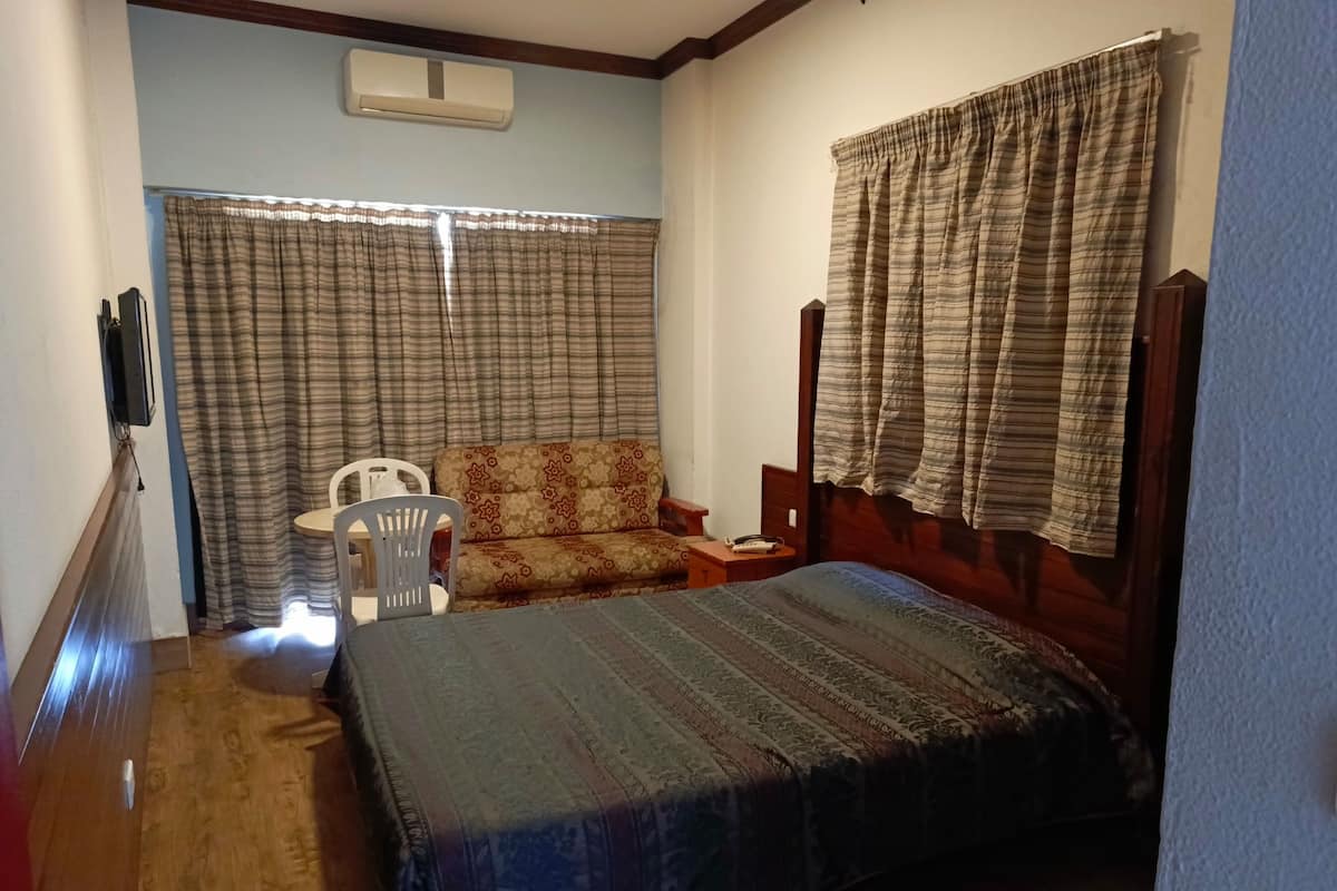 A bedroom with a bed, a chair, a table, and curtains.