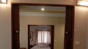 A bedroom with a bed, a chair, and a door leading to another room. - EdwardVHotel (Jounieh)
