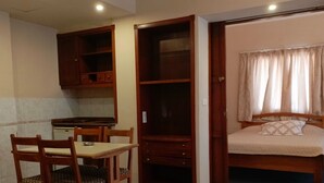 A compact room with a bed, a small table with chairs, a kitchenette, and a wardrobe. - EdwardVHotel (Jounieh)