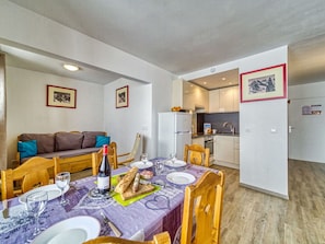 Espaço compacto com área de refeições, cozinha compacta e sofá.