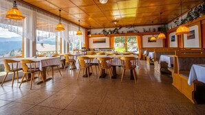 A dining area with wooden tables and chairs, large windows, and hanging pendant lights. - Stunning private villa for 36 guests with WIFI, TV and terrace (Bayerisch Eisenstein)