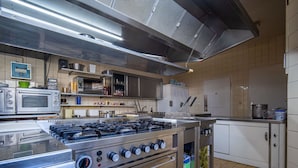 A commercial kitchen with stainless steel appliances, including a stove, ovens, and a microwave. - Stunning private villa for 36 guests with WIFI, TV and terrace (Bayerisch Eisenstein)