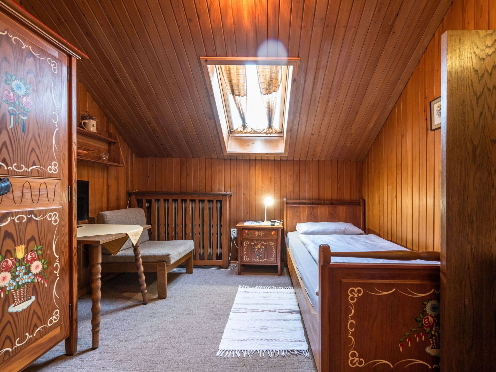 A cozy wooden room with a bed, a desk, and a chair.
