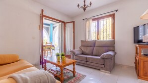Un salon avec un canapé, une table basse, un téléviseur et une fenêtre avec des rideaux.