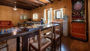 Une pièce chaleureuse avec des murs et un plafond en bois, un jeu de fléchettes, une table avec des chaises et un canapé.