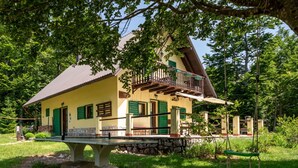 Une maison à deux étages avec un balcon, entourée de verdure.