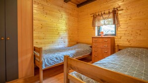 Une chambre dans un chalet en bois, avec deux lits superposés, une commode et une armoire.