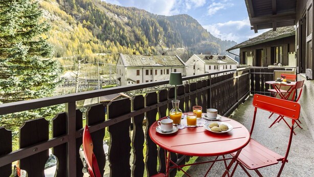 A balcony with a table set for breakfast, overlooking a mountainous village. - Cosy apartment for 5 guests with WIFI, TV, terrace and pets allowed (Isola)
