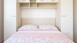 A bedroom with a bed, two pillows, a pink blanket, and a wooden headboard. - Beautiful apartment for 5 people with A/C, WIFI, TV, balcony and pets allowed (Solin)