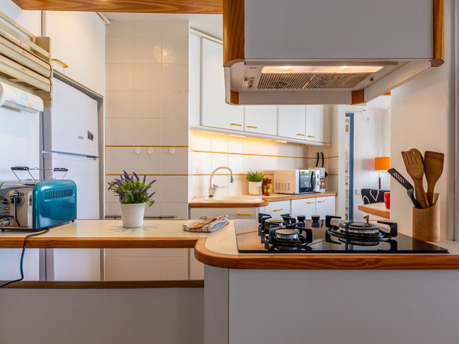 A compact kitchen with a gas stove, a toaster, and a microwave.