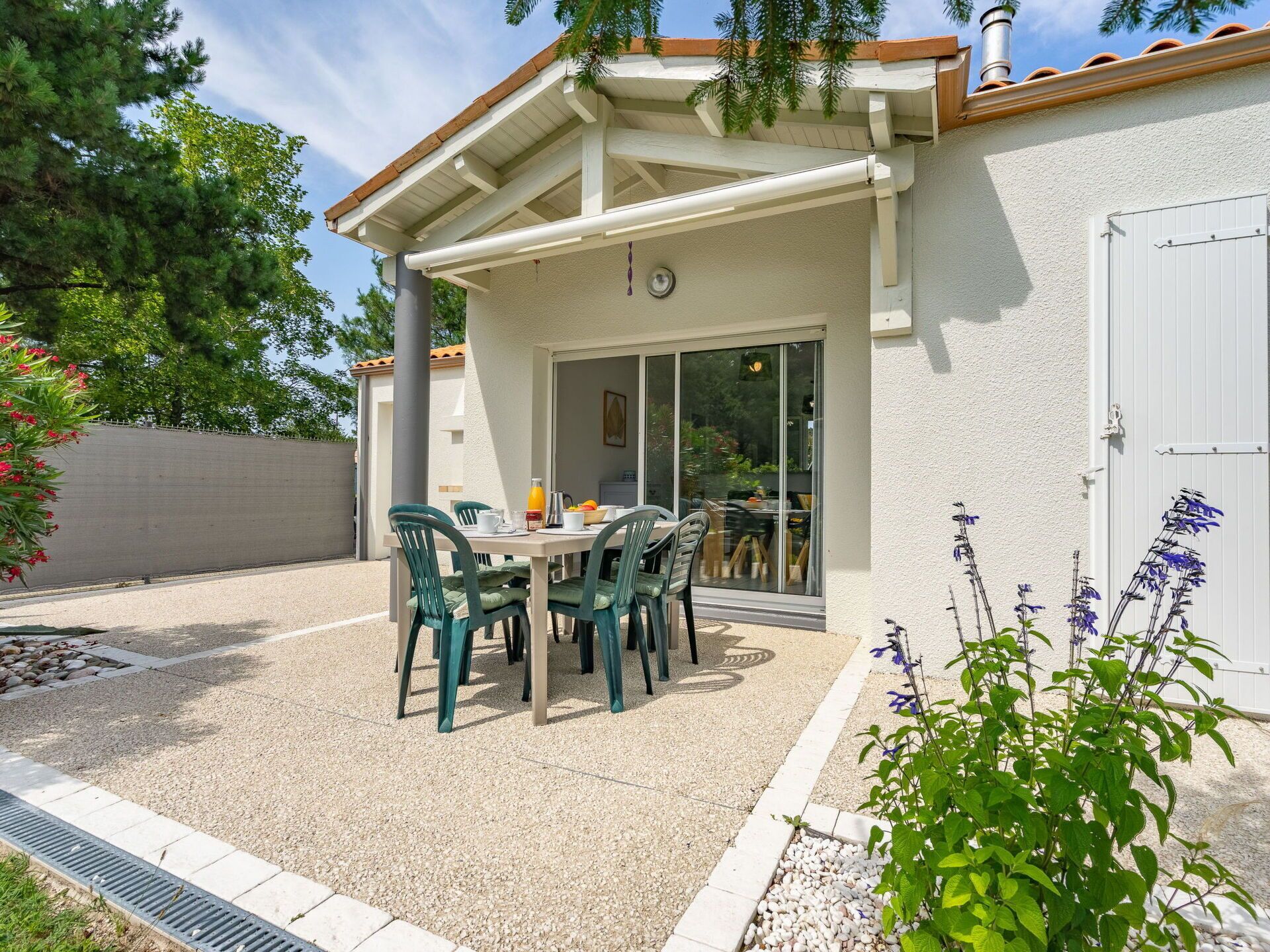 Un patio con mesa y sillas, una zona de estar cubierta y vistas hacia la casa.