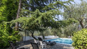 Un área junto a la piscina con sillones de descanso y un suelo de baldosas de piedra.