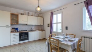 Una cocina moderna con armarios blancos, una estufa a gas y un comedor con una mesa dispuesta para cuatro.