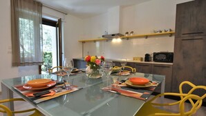 A modern kitchen with a glass dining table, yellow chairs, and a vase of flowers. - Beautiful apartment for 6 people with WIFI, A/C, TV and pets allowed (Cosio Valtellino)