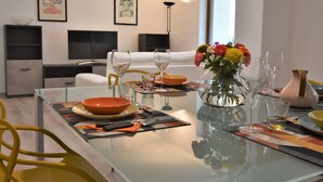 A modern dining area with a glass table set for two, featuring a vase of flowers, wine glasses, and cutlery. - Beautiful apartment for 6 people with WIFI, A/C, TV and pets allowed (Cosio Valtellino)