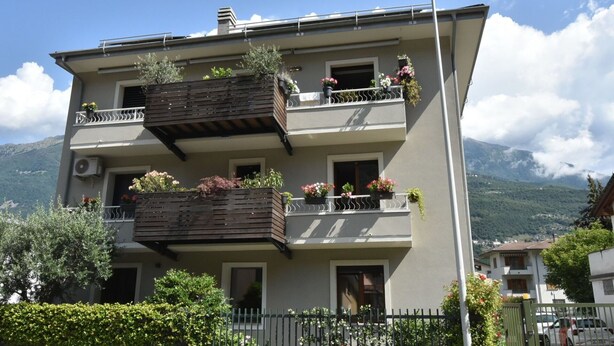 A multi-story building with balconies, each adorned with potted plants and flowers. - Beautiful apartment for 6 people with WIFI, A/C, TV and pets allowed (Cosio Valtellino)