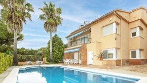 A two-story building with a swimming pool, outdoor seating, and palm trees. - Nice apartment for 8 people with A/C, private pool, WIFI, TV, patio and panoramic view (Calonge)