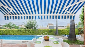 An outdoor patio with a pool, a table set for dining, and a striped canopy overhead. - Nice apartment for 8 people with A/C, private pool, WIFI, TV, patio and panoramic view (Calonge)