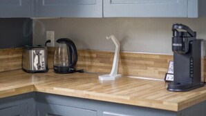Een keuken met grijze kastjes, een houten aanrecht, een broodrooster, een koffiezetapparaat en een waterkoker.