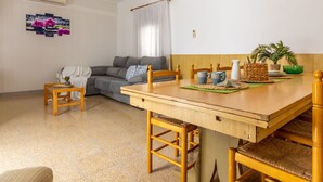 A cozy living room with a wooden dining table, a grey sofa, and a small coffee table. - Wonderful private villa for 7 guests with WIFI, A/C, TV and pets allowed (Amposta)