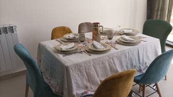 A dining table set with plates, glasses, and a pitcher, surrounded by chairs with a patterned tablecloth.