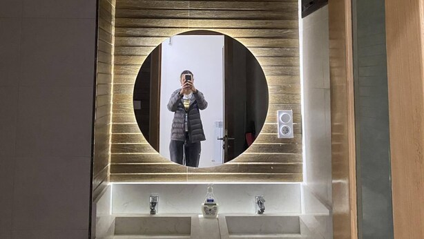 Un baño con un espejo grande, dos lavamanos y un techo de madera.