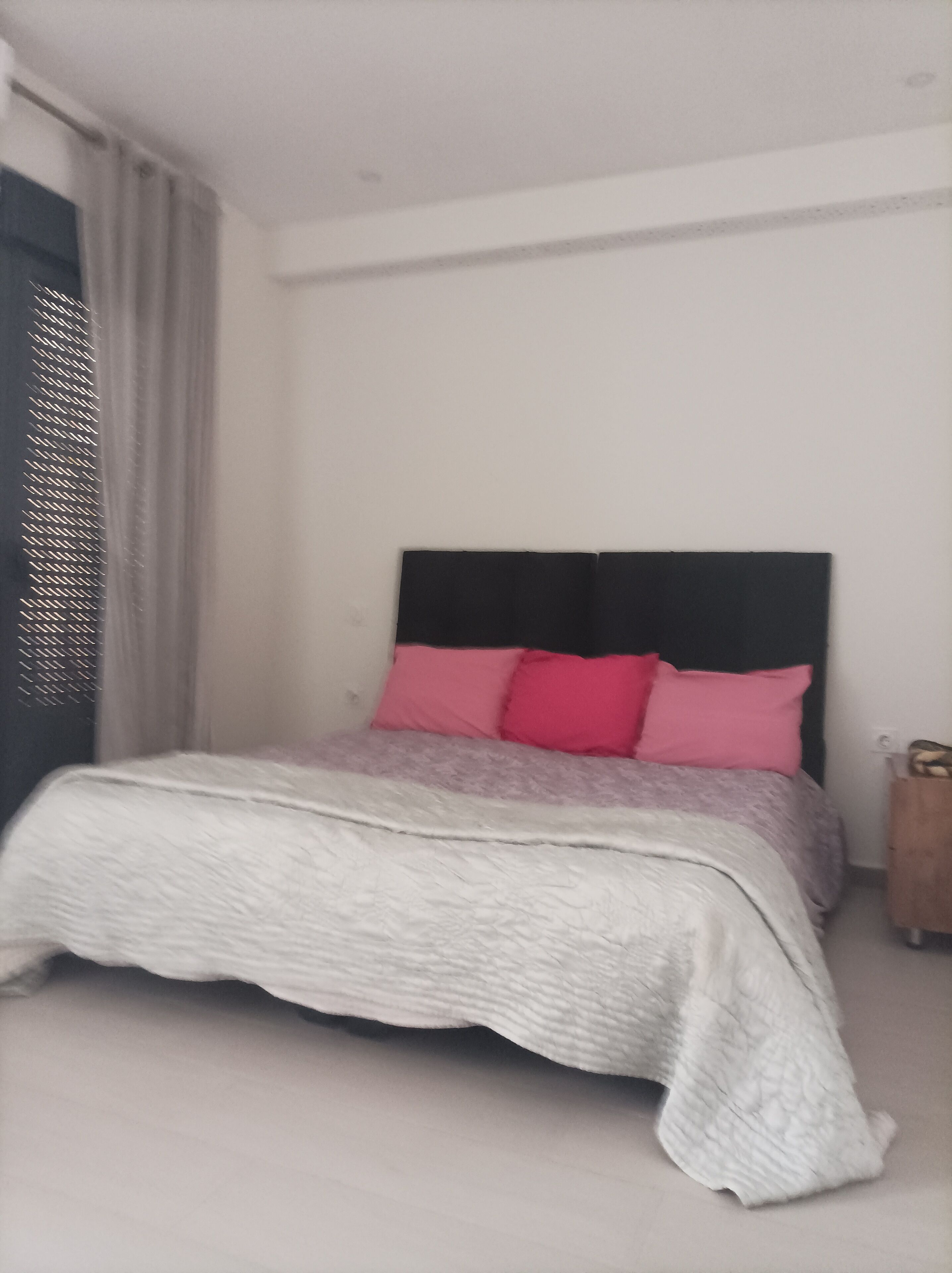 Quarto com cama, cabeceira e mesa de cabeceira.