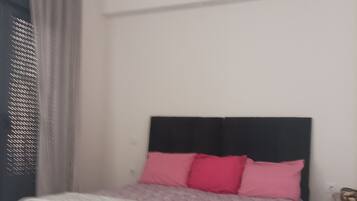 Quarto com cama, cabeceira e mesa de cabeceira.