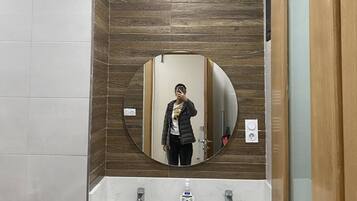 A bathroom with a wooden panel wall, a round mirror, and two sinks.