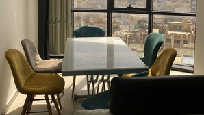 Una habitación moderna con un gran ventanal, una mesa de vidrio y cuatro sillas.