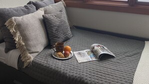 Una stanza accogliente con una seduta finestrata, un piatto con pasticcini, una tazza e una rivista.