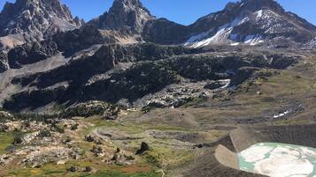A mountainous landscape with rugged peaks, a winding path, and a small body of water.