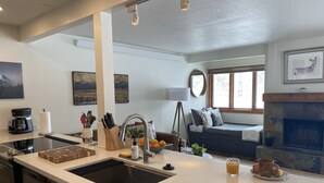Una cucina moderna con una grande isola, elettrodomestici integrati e un'area salotto con camino.