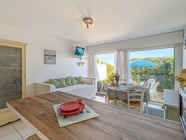 Enjoy a room with a large window offering a view of the outdoors, a dining table, a sofa, and a flat-screen TV.