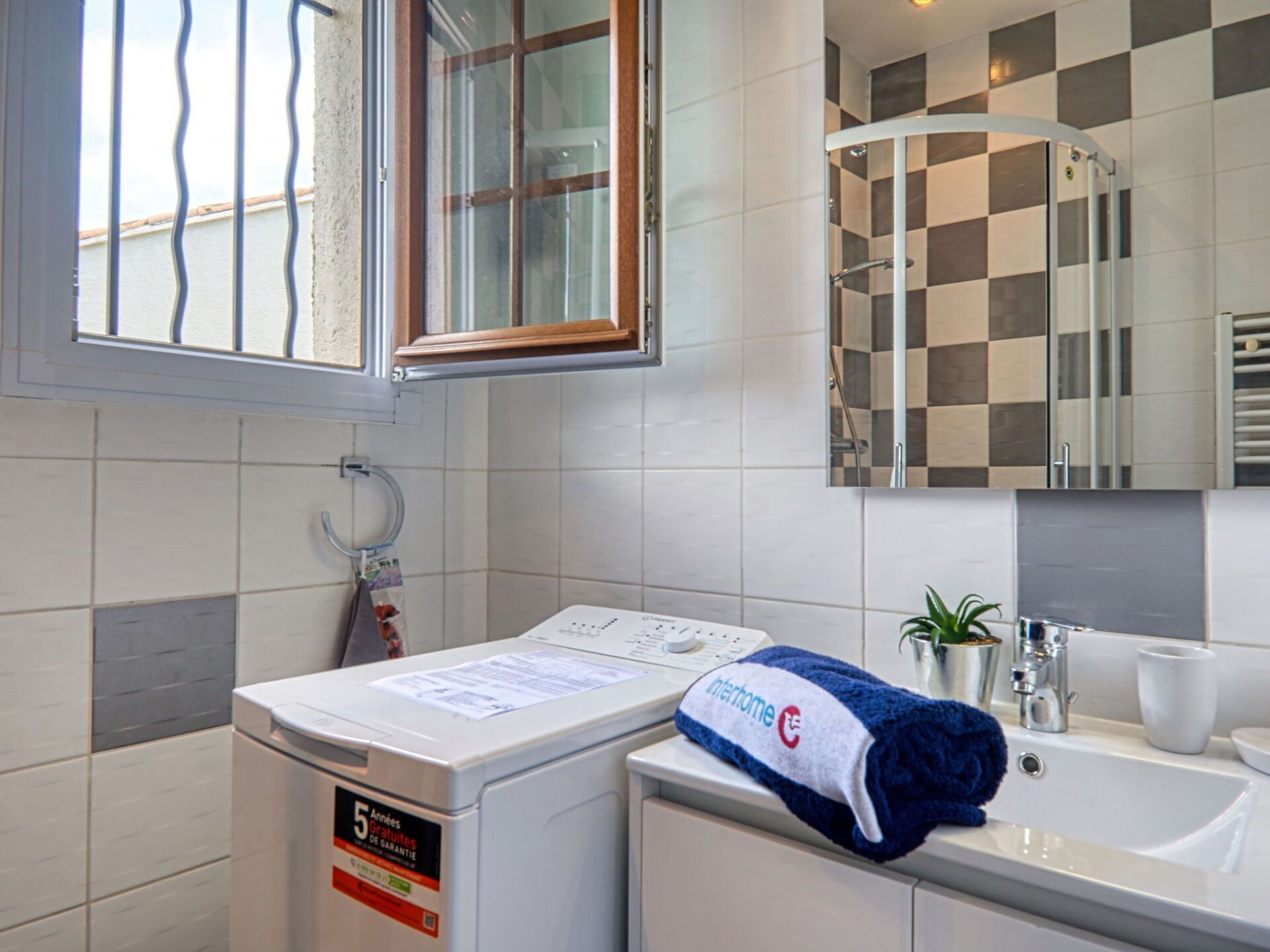 A hotel bathroom with a washing machine, a towel, a sink, and a mirror.